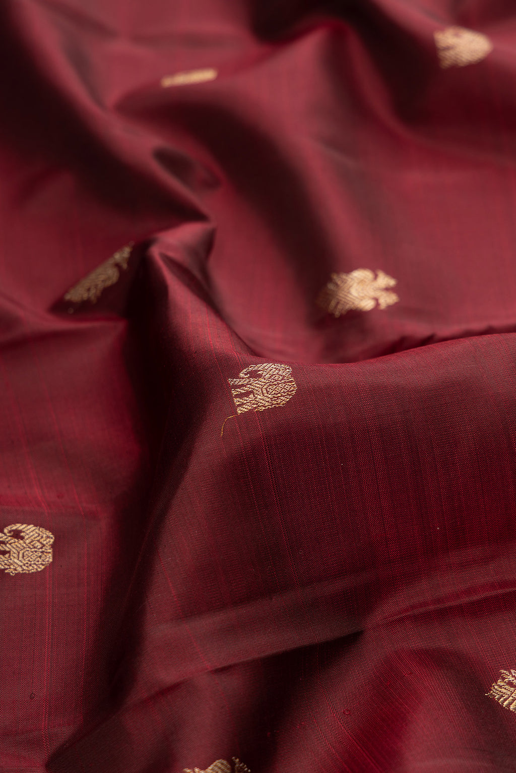 Close up of Pure Silk Maroon Kanjivaram Saree with Zari Butta on the body and Fancy Border.  displaying folds
