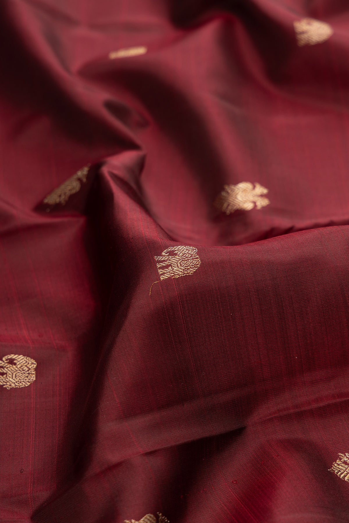 Close up of Pure Silk Maroon Kanjivaram Saree with Zari Butta on the body and Fancy Border.  displaying folds