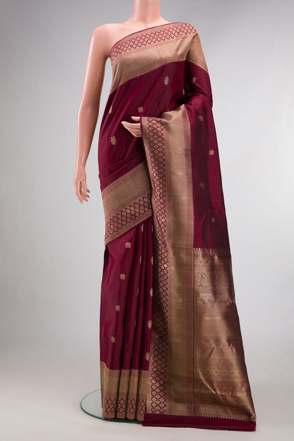 Pure Silk Maroon Kanjivaram Saree with Zari Butta on the body and Fancy Border.  displayed on a mannequin