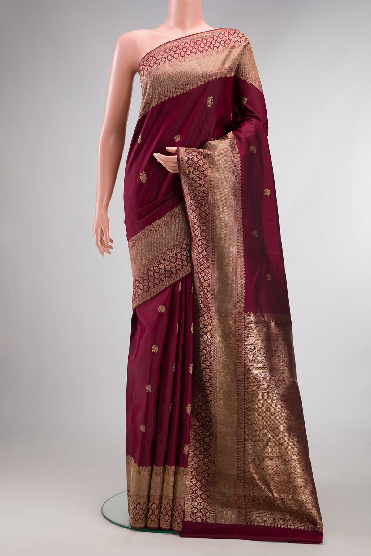 Pure Silk Maroon Kanjivaram Saree with Zari Butta on the body and Fancy Border.  displayed on a mannequin