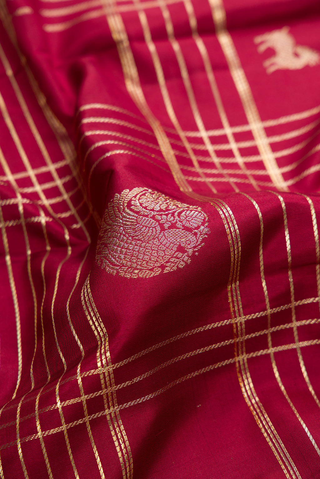 Close up of Pure Silk Maroon Kanchipuram Saree with Checked design on the body and Zari Border.  displaying folds