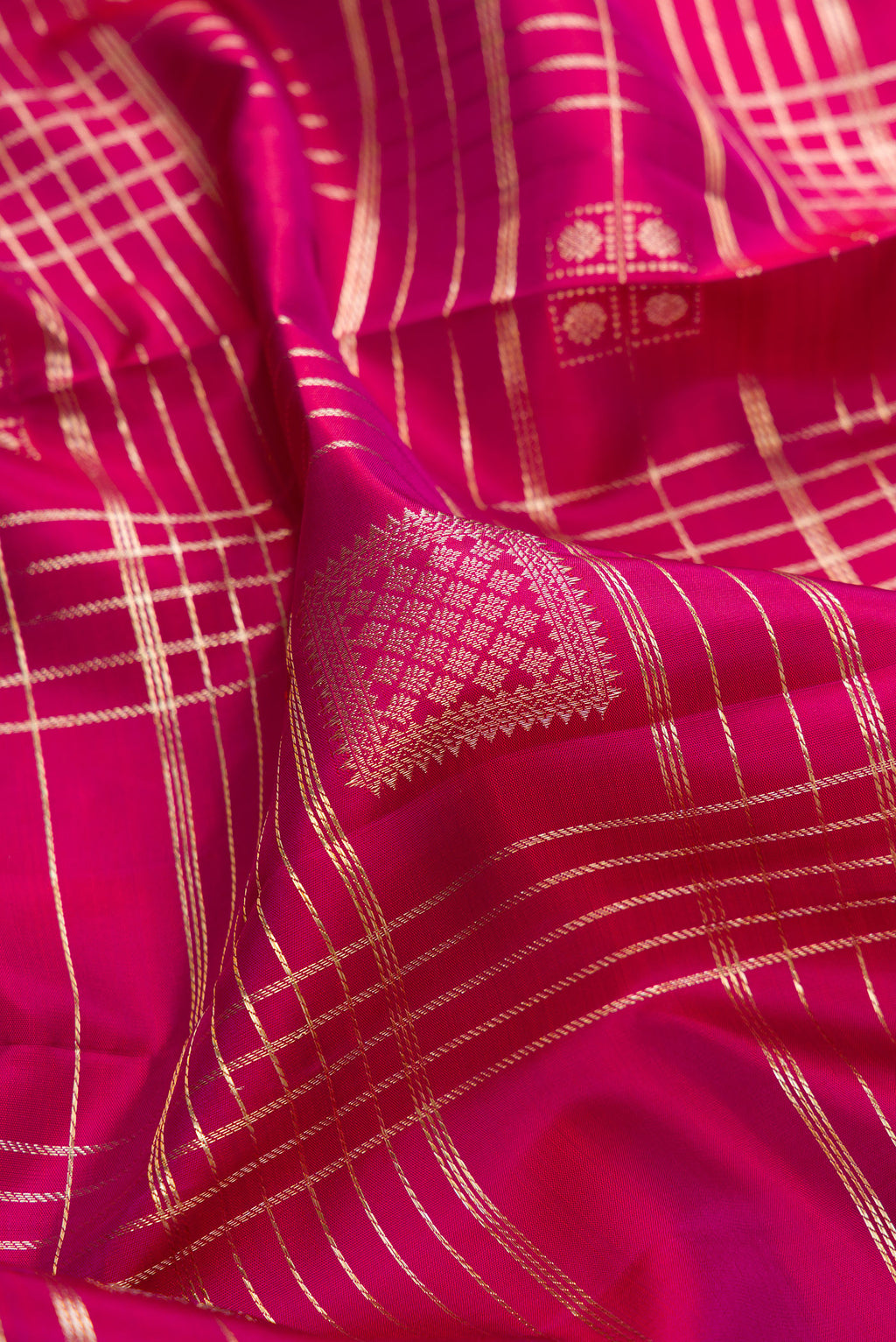 Close up of Pure Silk Dark Pink Kanchipuram Saree with Checked design on the body and Zari Border.  displaying folds