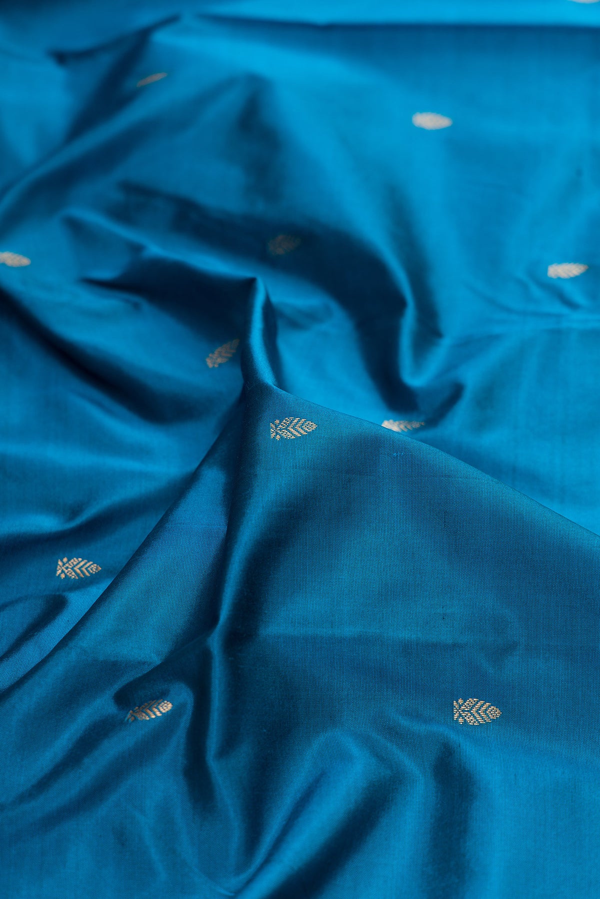 Close up of Pure Silk Peacock Blue Kanchipuram Saree with Zari Butta on the body and Zari Border.  displaying folds
