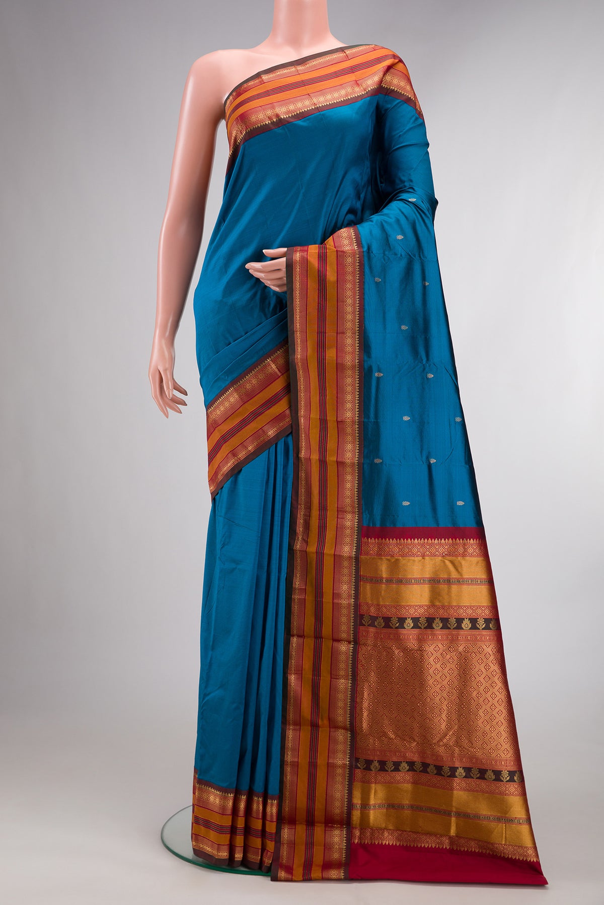 Pure Silk Peacock Blue Kanchipuram Saree with Zari Butta on the body and Zari Border.  displayed on a mannequin