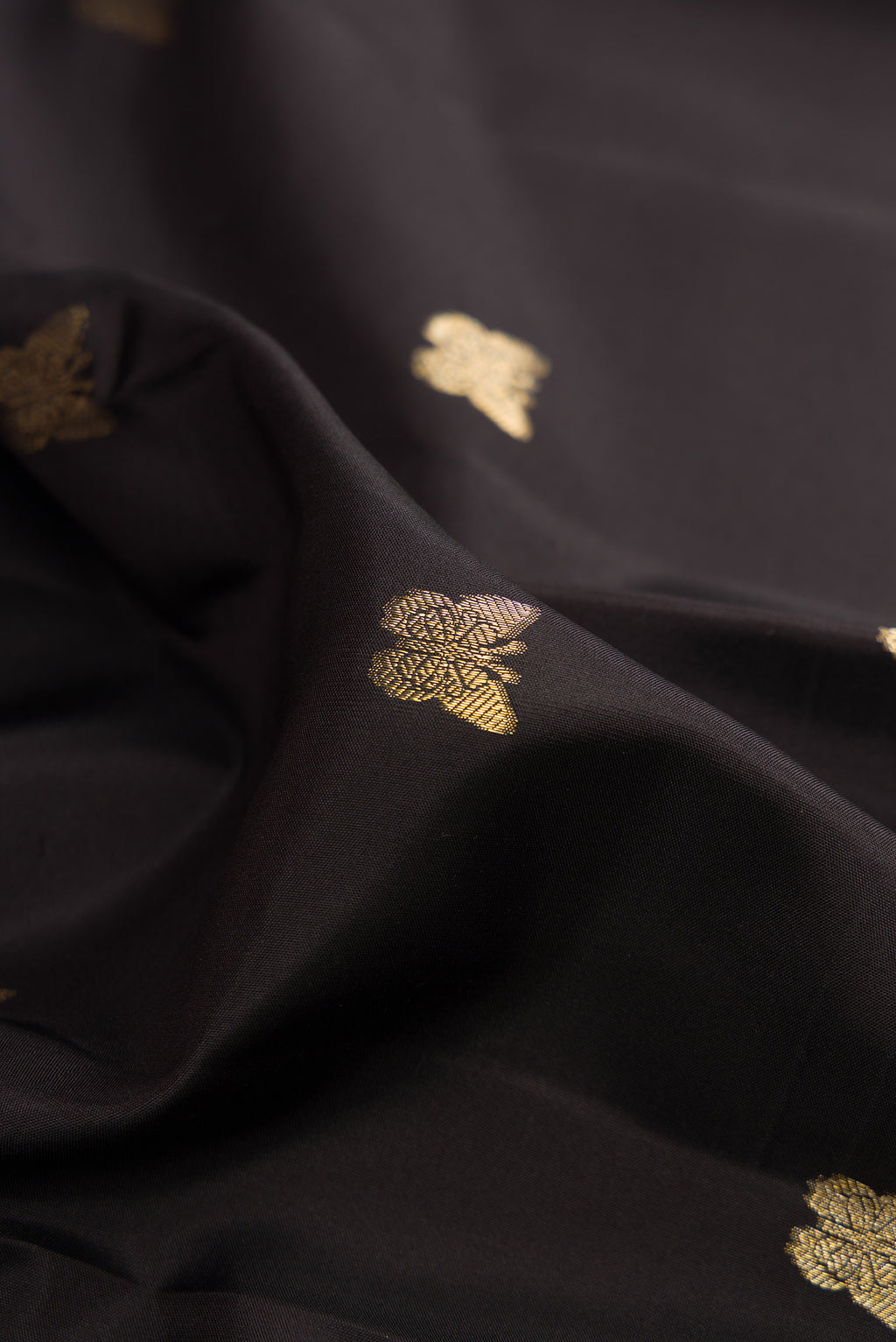 Close up of Pure Silk Black Kanjivaram Saree with Zari Butta on the body and Zari Border.  displaying folds