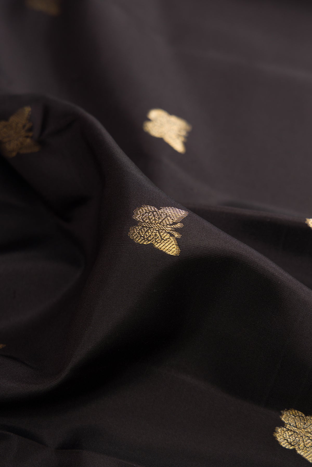 Close up of Pure Silk Black Kanjivaram Saree with Zari Butta on the body and Zari Border.  displaying folds