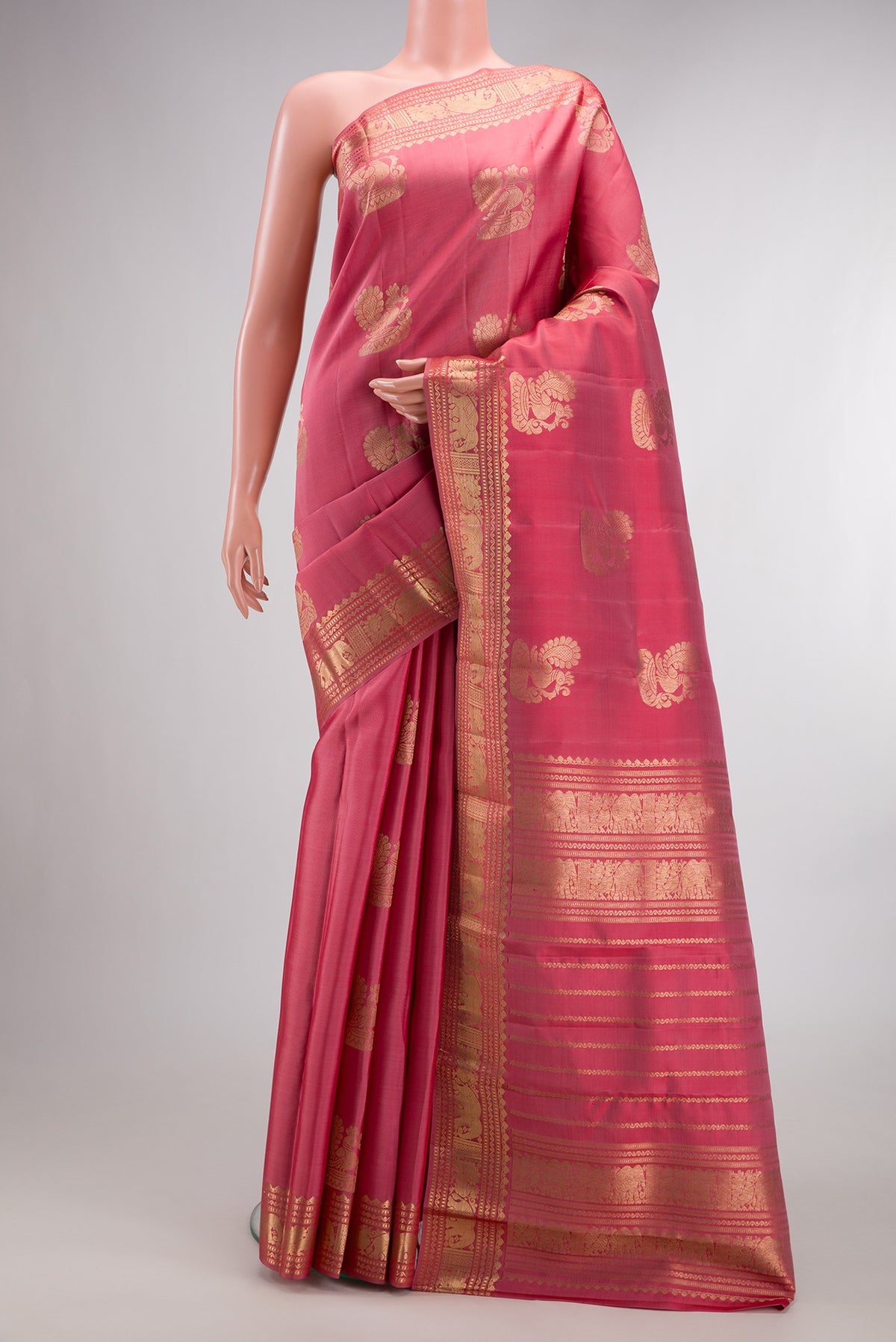 Pure Silk Coral Kanjivaram Saree with Zari Butta on the body and Zari Border.  displayed on a mannequin