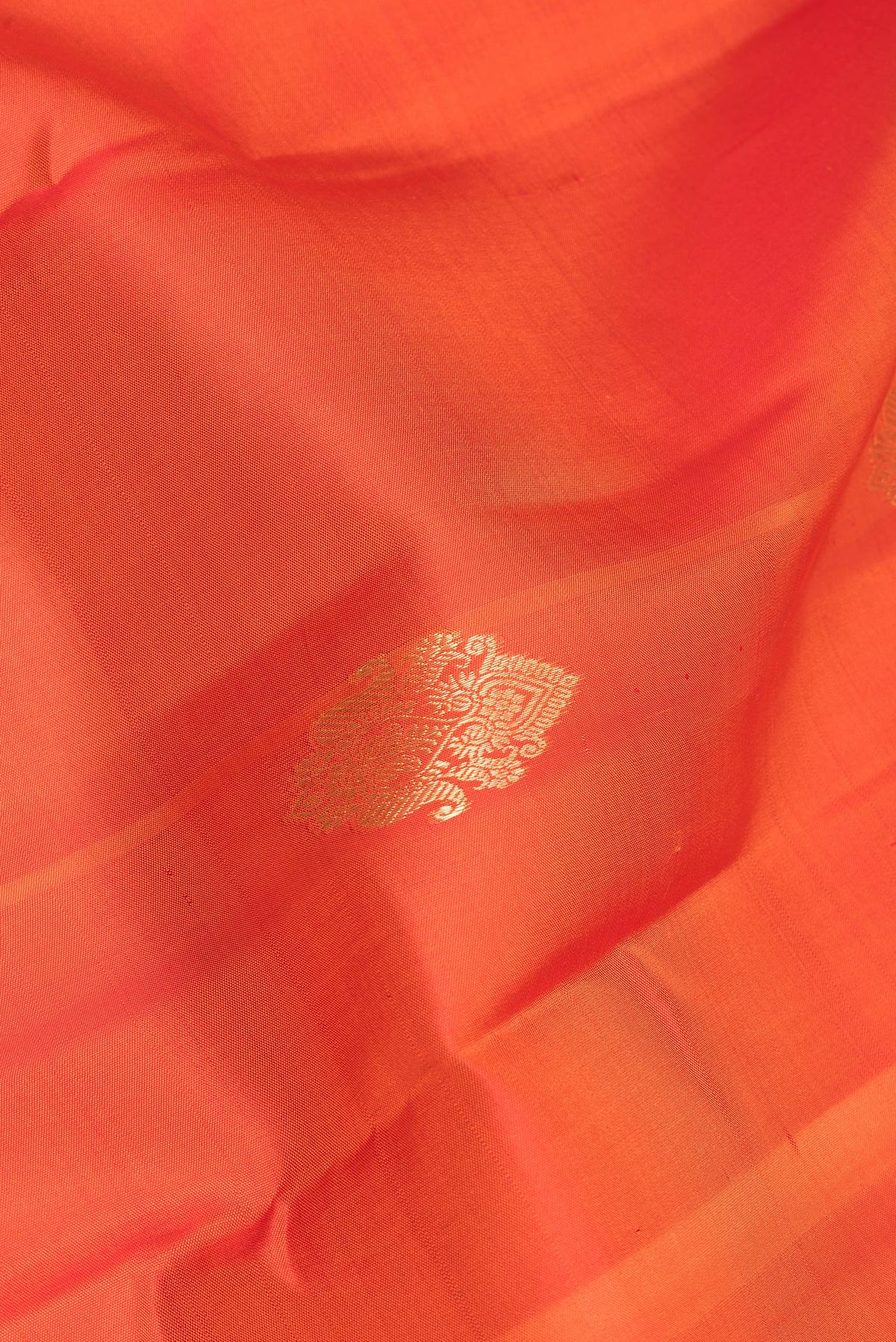 Close up of Pure Silk Orange Kanjivaram Saree with Zari Butta on the body and Zari Border.  displaying folds