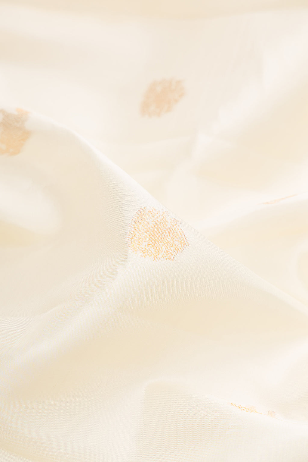 Close up of Pure Silk Off White Kanchipuram Saree with Zari Butta on the body and Zari Border.  displaying folds