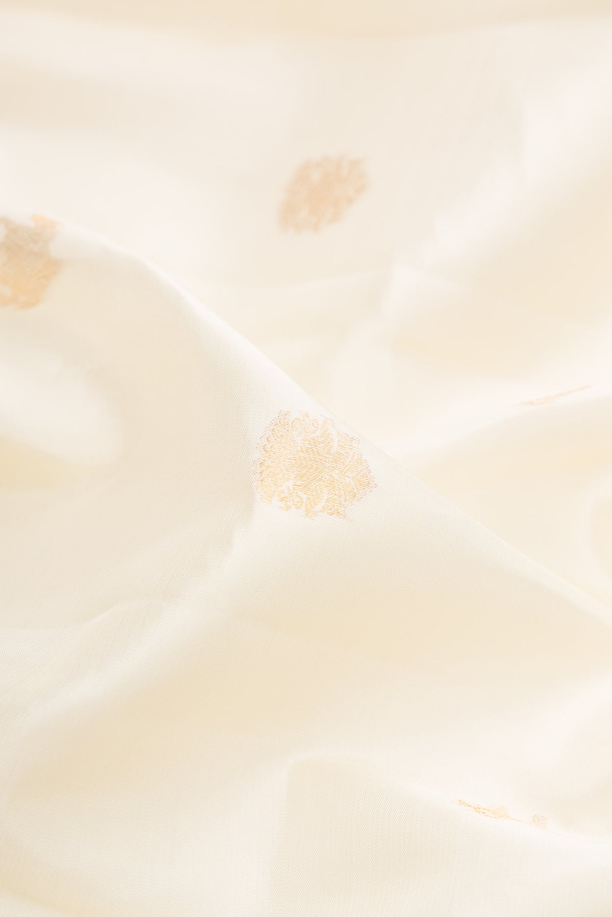 Close up of Pure Silk Off White Kanchipuram Saree with Zari Butta on the body and Zari Border.  displaying folds