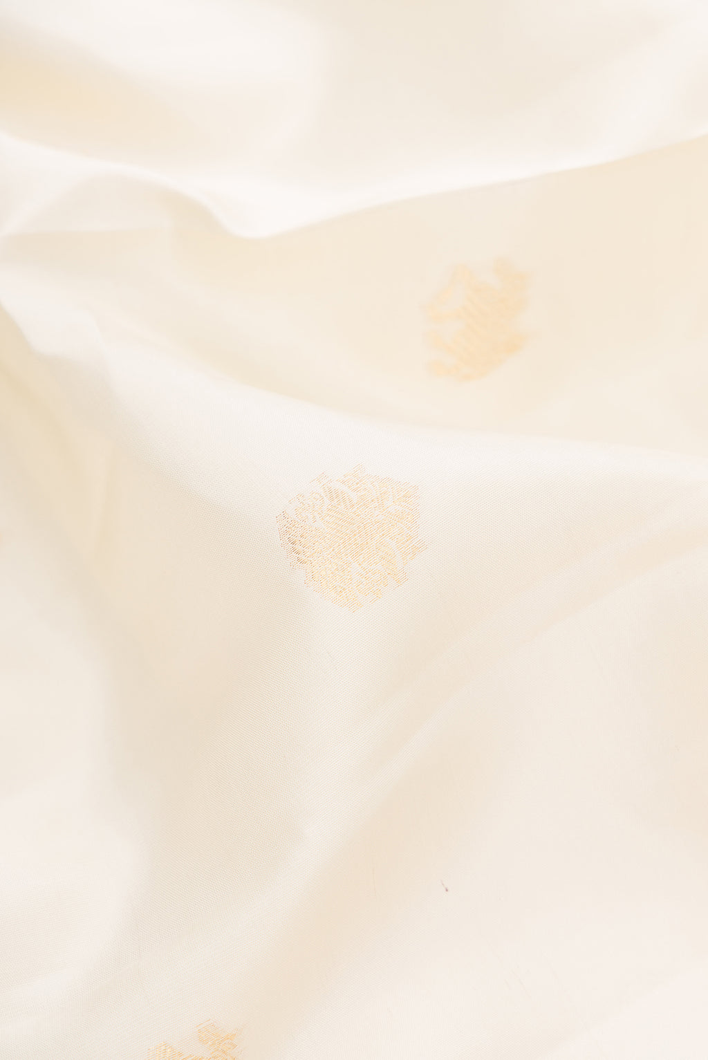 Close up of Pure Silk Off White Kanchipuram Saree with Zari Butta on the body and Zari Border.  displaying folds