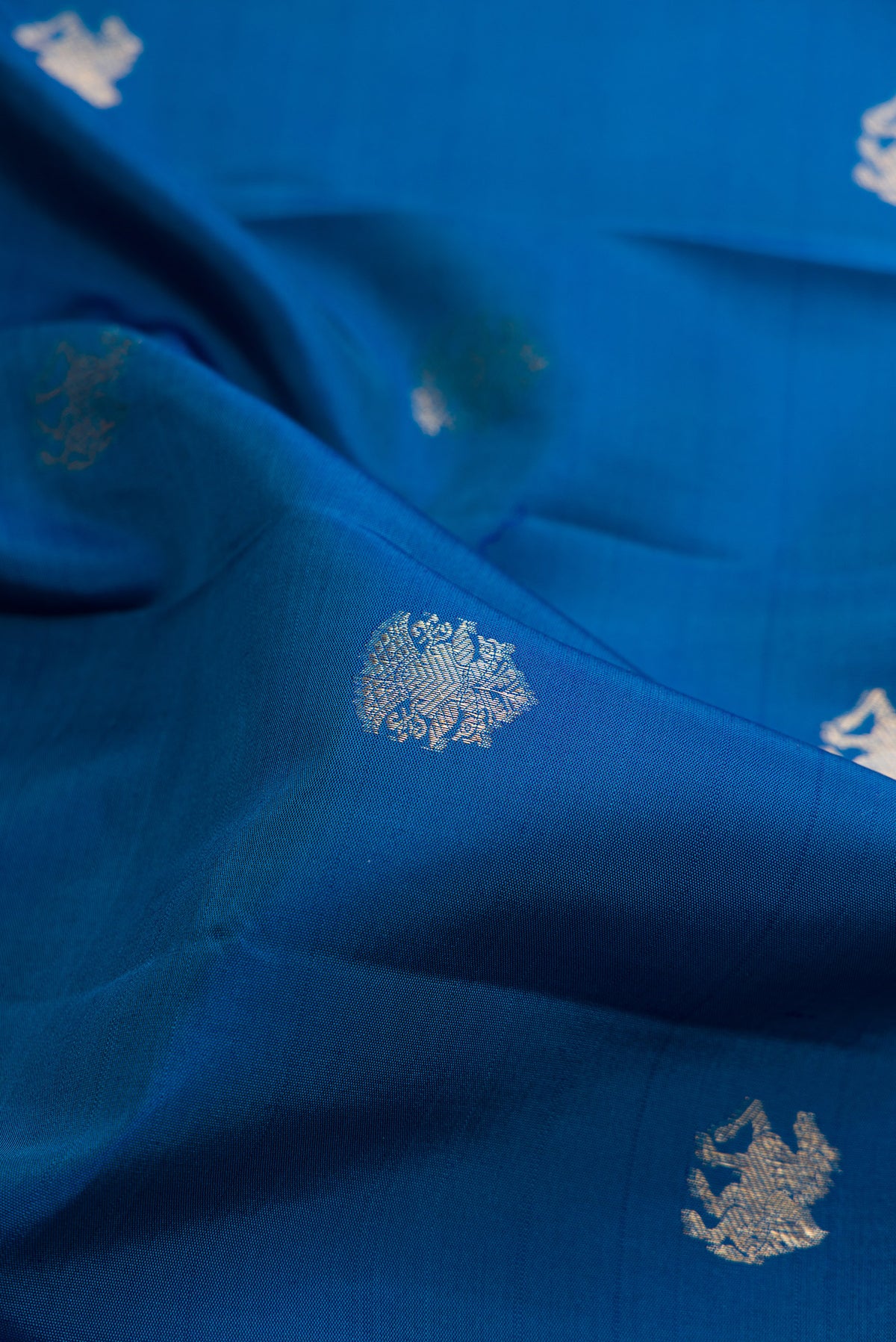 Close up of Pure Silk Blue Kanchipuram Saree with Zari Butta on the body and Zari Border.  displaying folds
