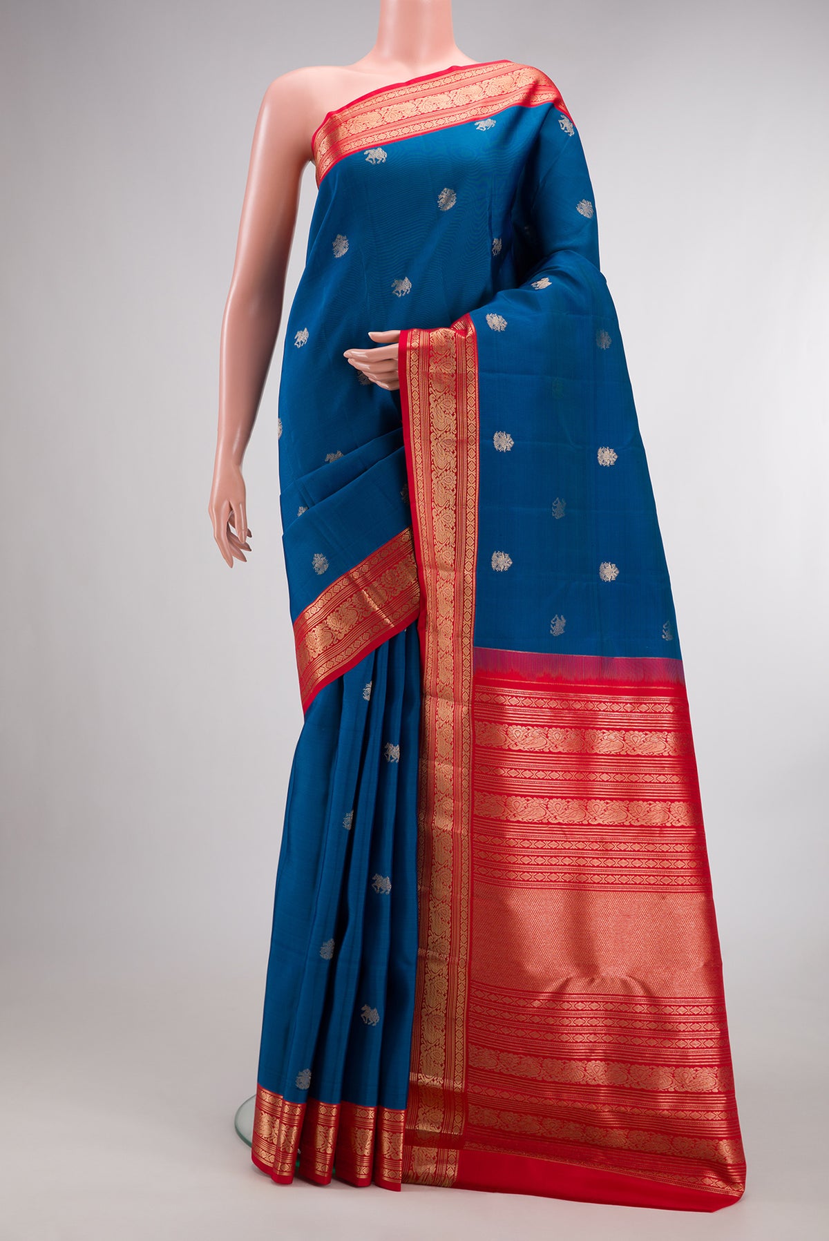 Pure Silk Blue Kanchipuram Saree with Zari Butta on the body and Zari Border.  displayed on a mannequin