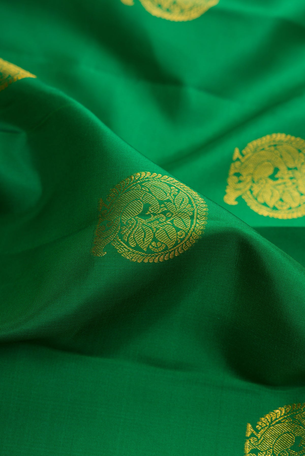 Close up of Pure Silk Green Kanchipuram Saree with Zari Butta on the body and Zari Border.  displaying folds
