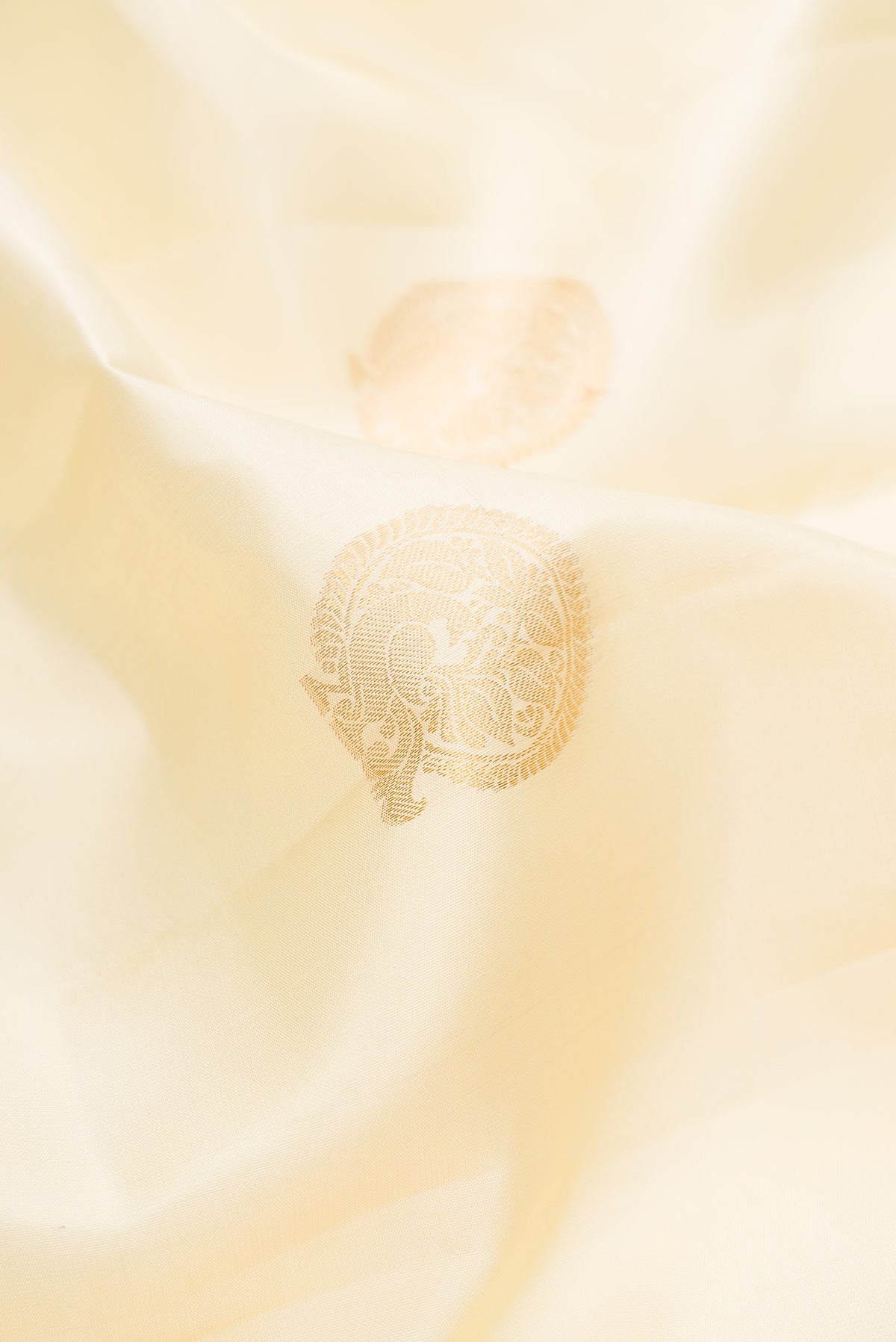 Close up of Pure Silk Cream Kanchipuram Saree with Zari Butta on the body and Zari Border.  displaying folds