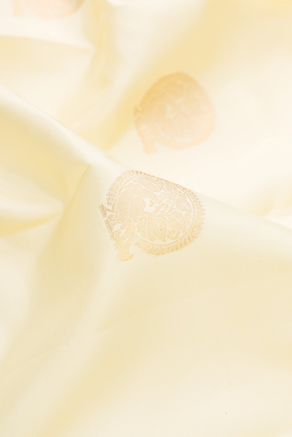 Close up of Pure Silk Cream Kanchipuram Saree with Zari Butta on the body and Zari Border.  displaying folds