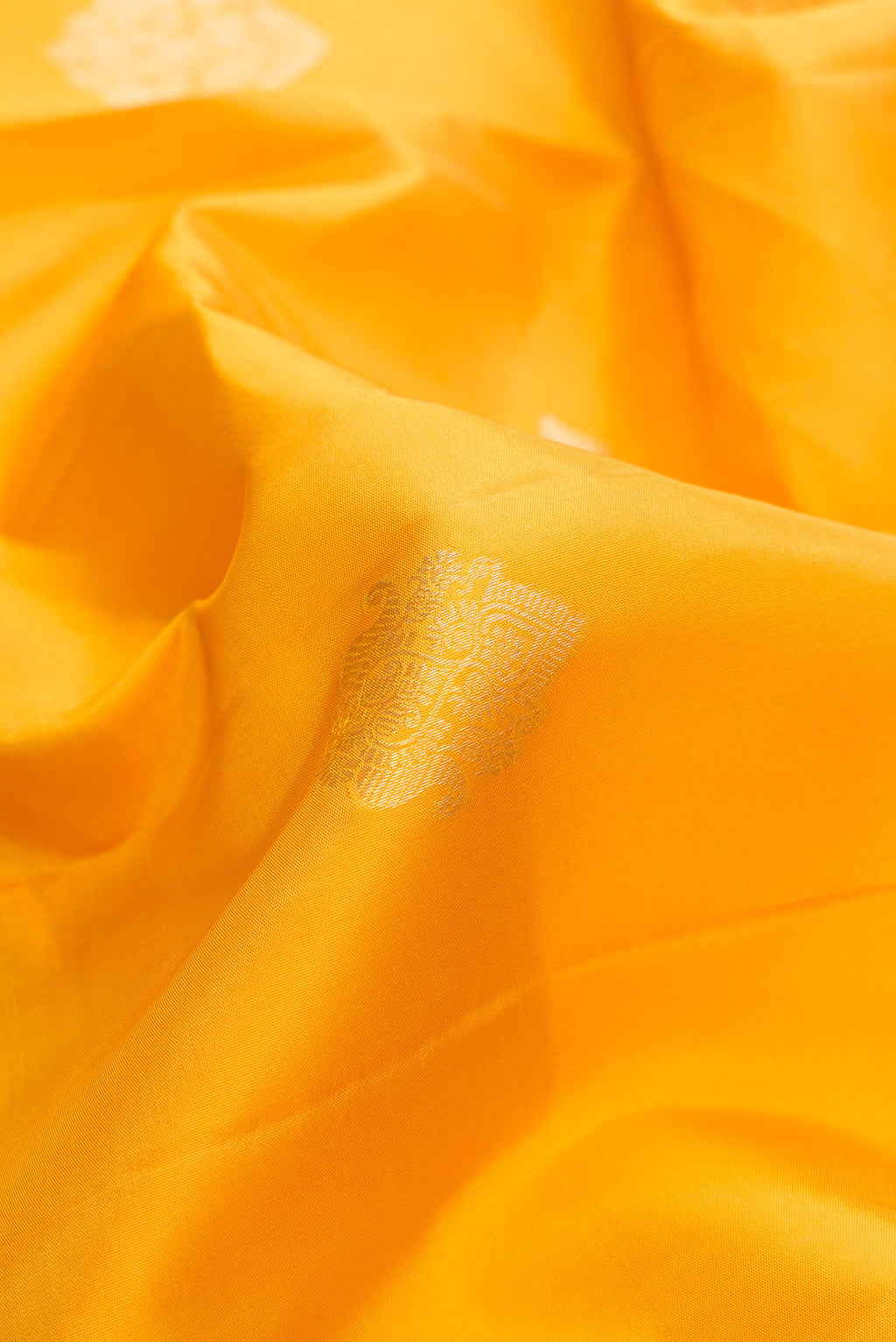 Close up of Pure Silk Yellow Kanchipuram Saree with Zari Butta on the body and Zari Border.  displaying folds