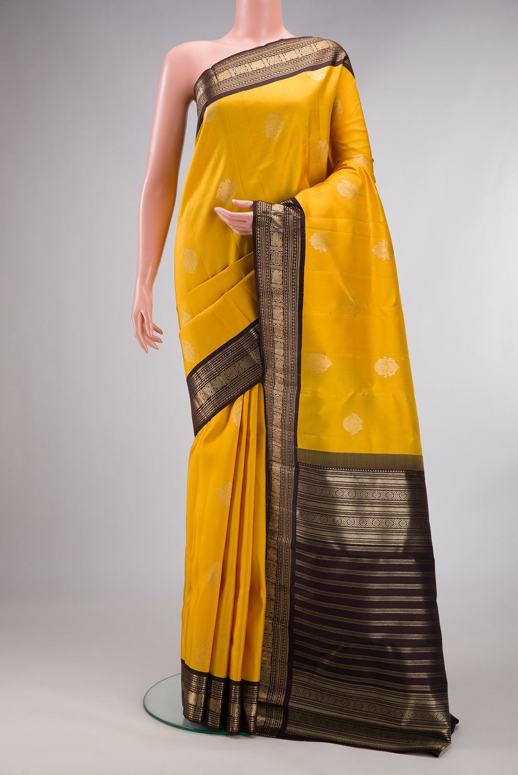 Pure Silk Yellow Kanchipuram Saree with Zari Butta on the body and Zari Border.  displayed on a mannequin