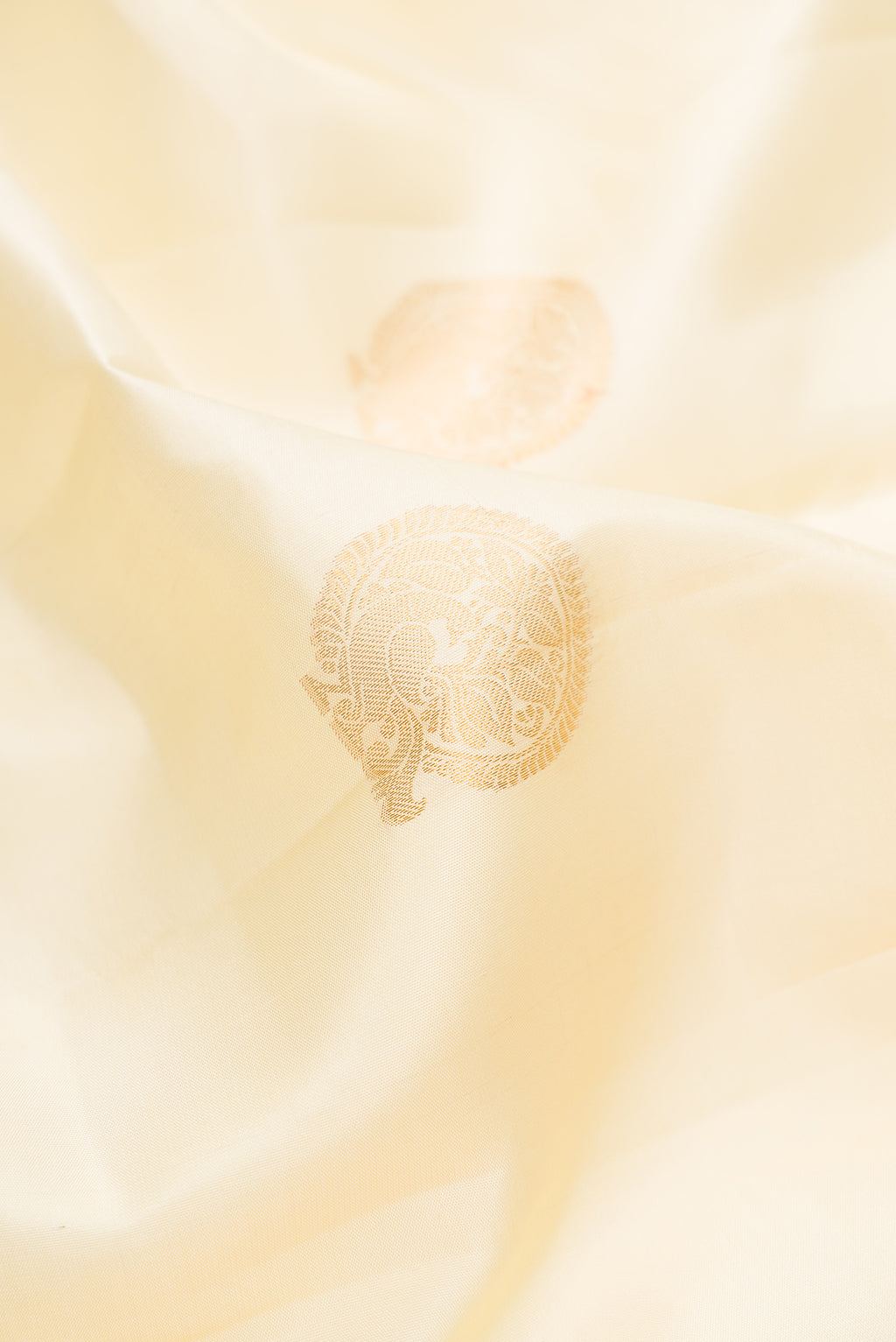 Close up of Pure Silk Cream Kanchipuram Saree with Zari Butta on the body and Zari Border.  displaying folds
