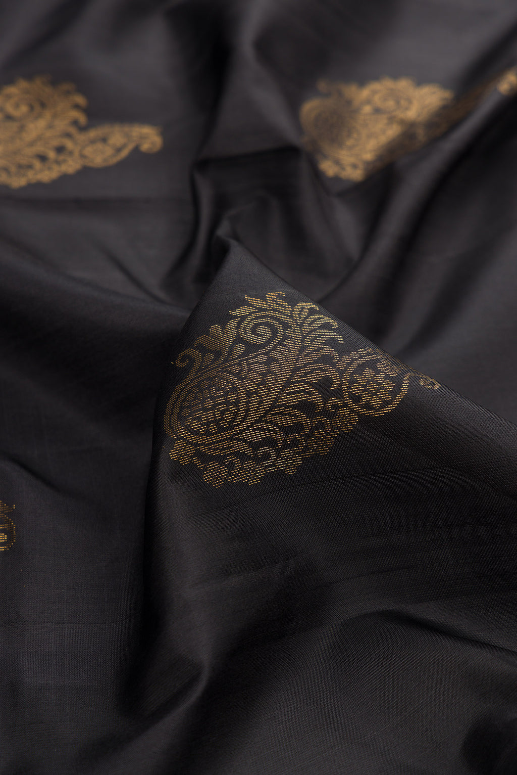 Close up of Pure Silk Black Soft Saree with Zari Butta on the body and Zari Border.  displaying folds