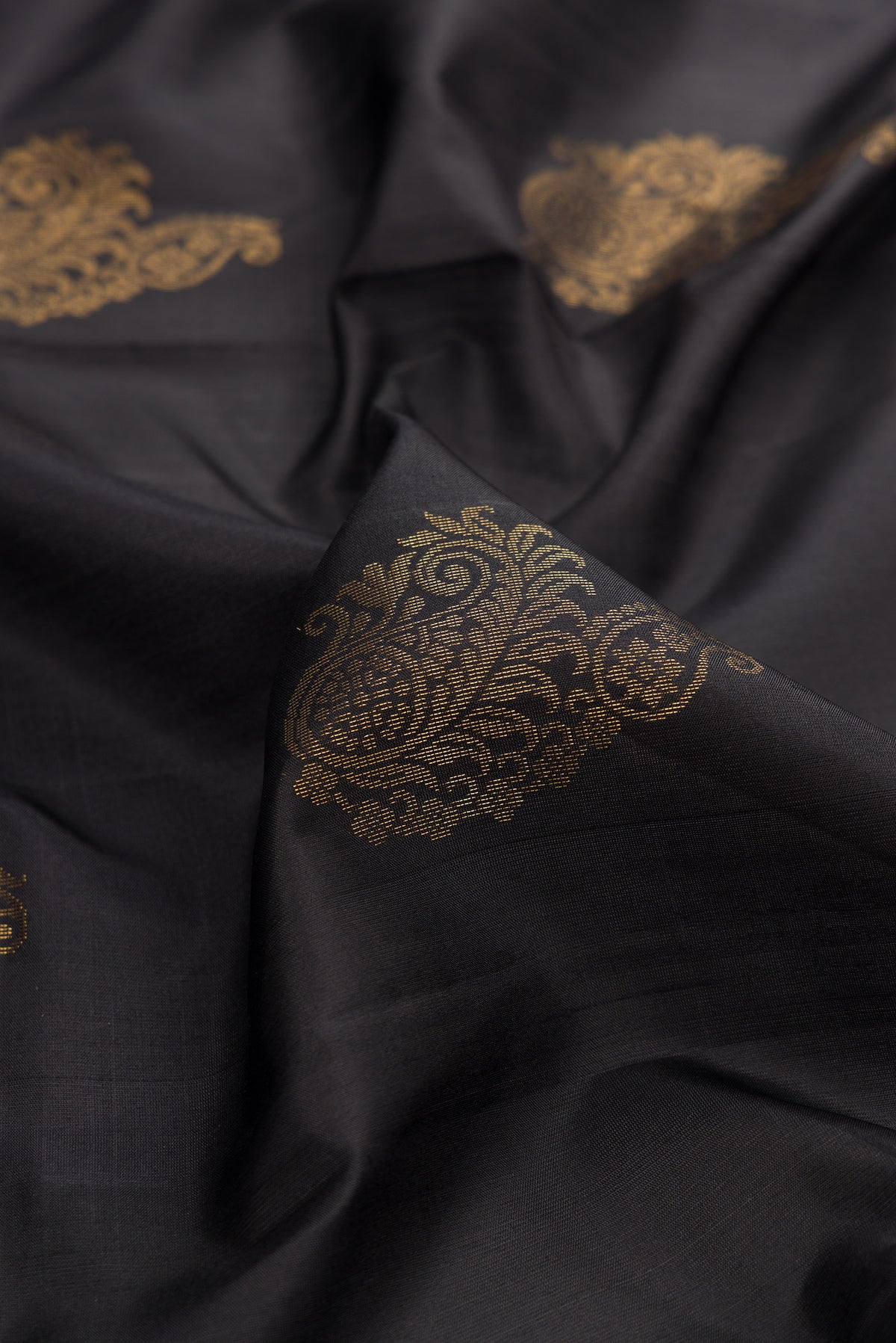 Close up of Pure Silk Black Soft Saree with Zari Butta on the body and Zari Border.  displaying folds