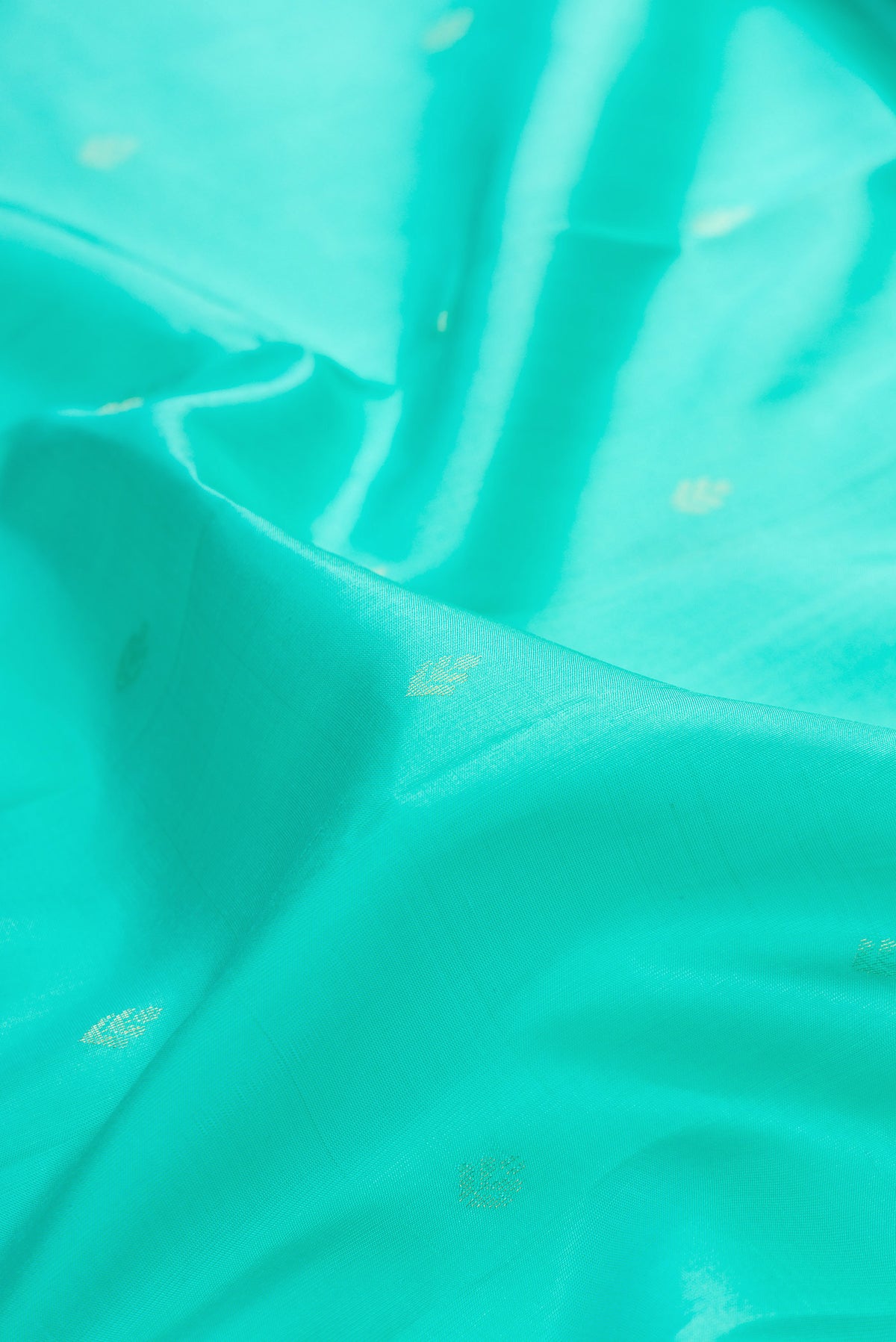 Close up of Pure Silk Sea Green Soft Saree with Zari Butta on the body and Zari Border.  displaying folds