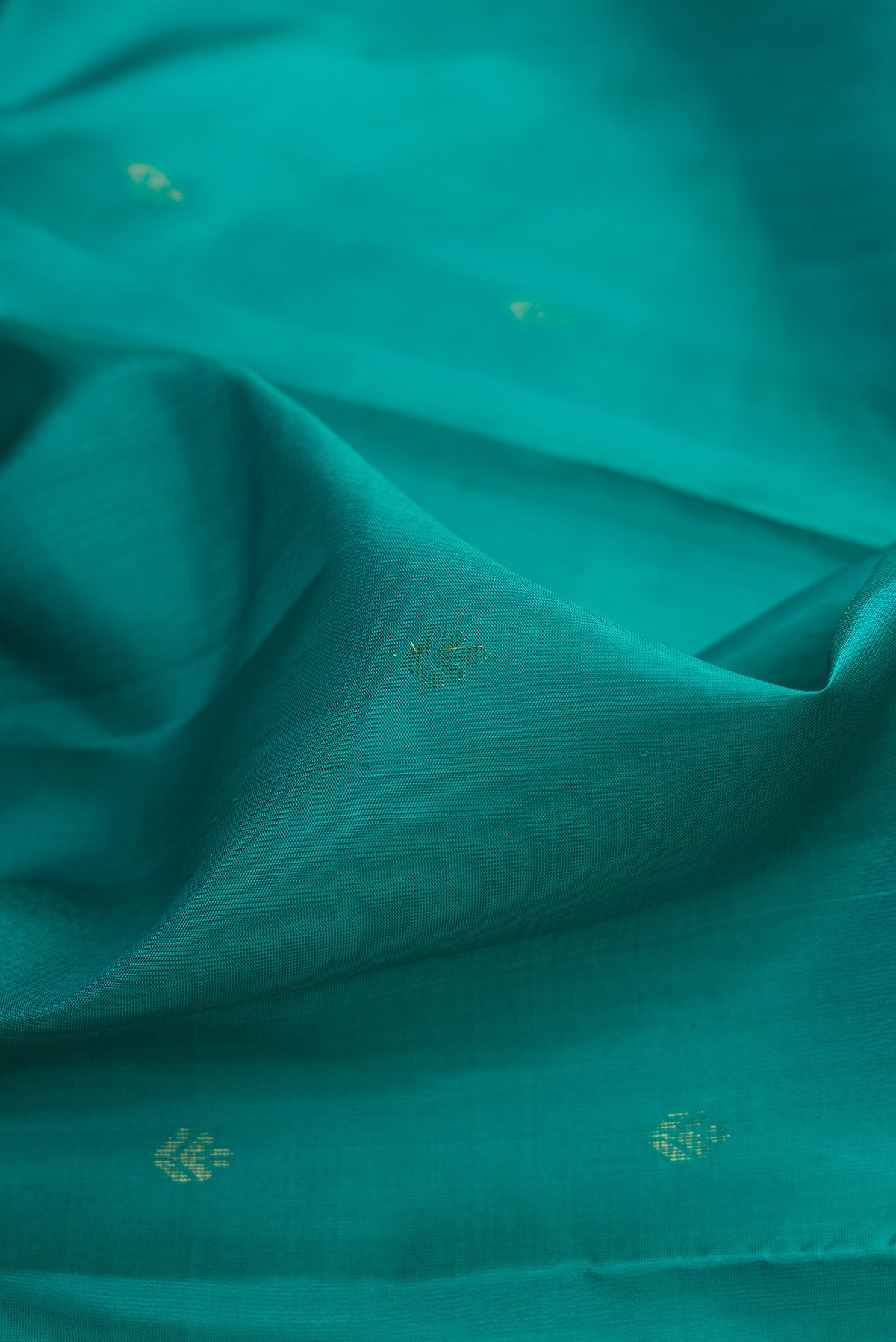 Close up of Pure Silk Sea Green Soft Saree with Zari Butta on the body and Zari Border.  displaying folds