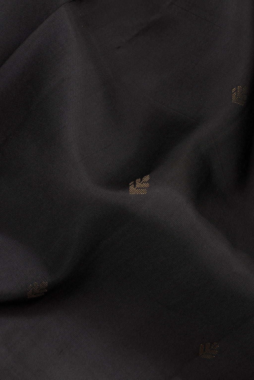 Close up of Pure Silk Black Soft Saree with Zari Butta on the body and Zari Border.  displaying folds