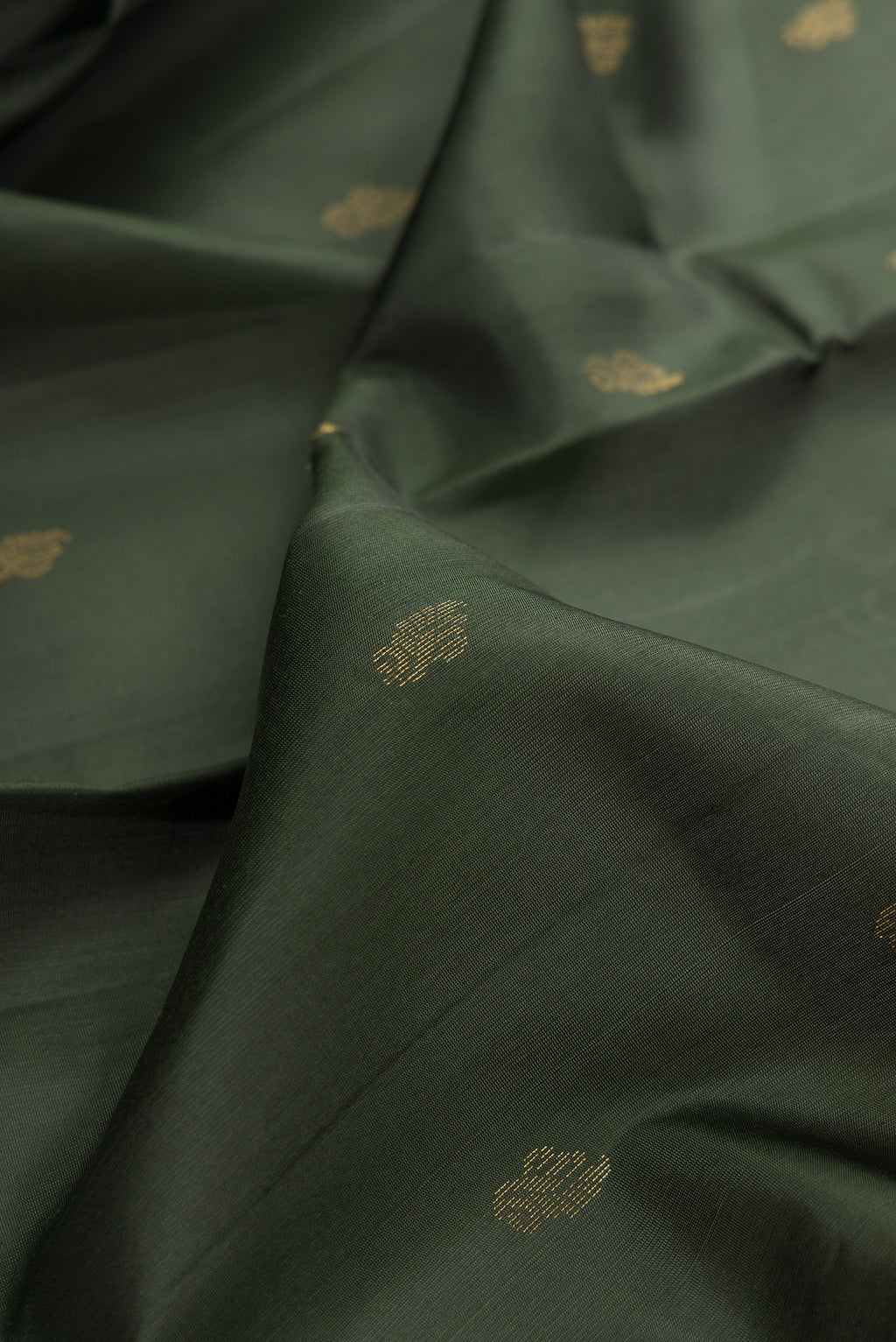 Close up of Pure Silk Bottle Green Soft Saree with Zari Butta on the body and Zari Border.  displaying folds