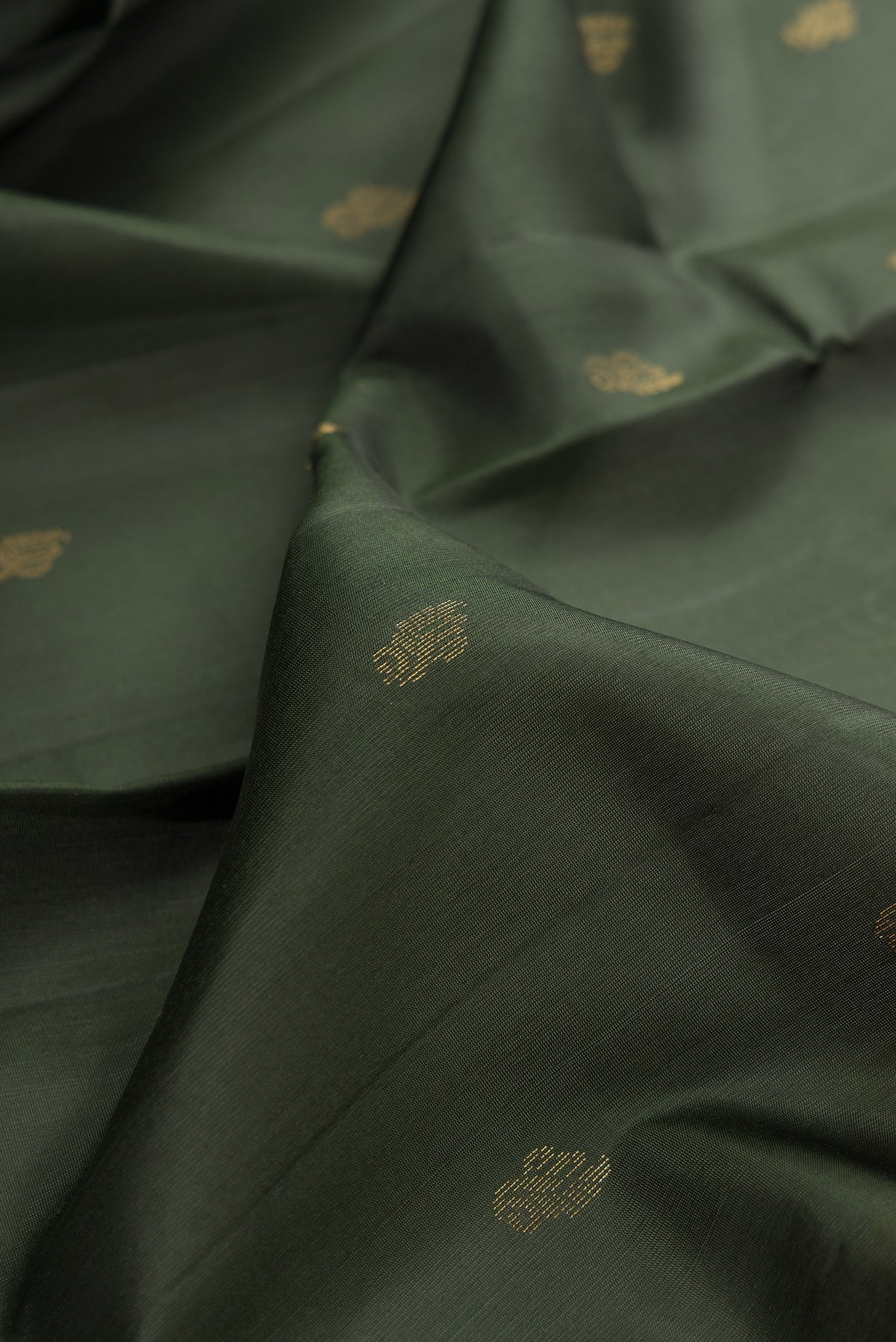 Close up of Pure Silk Bottle Green Soft Saree with Zari Butta on the body and Zari Border.  displaying folds
