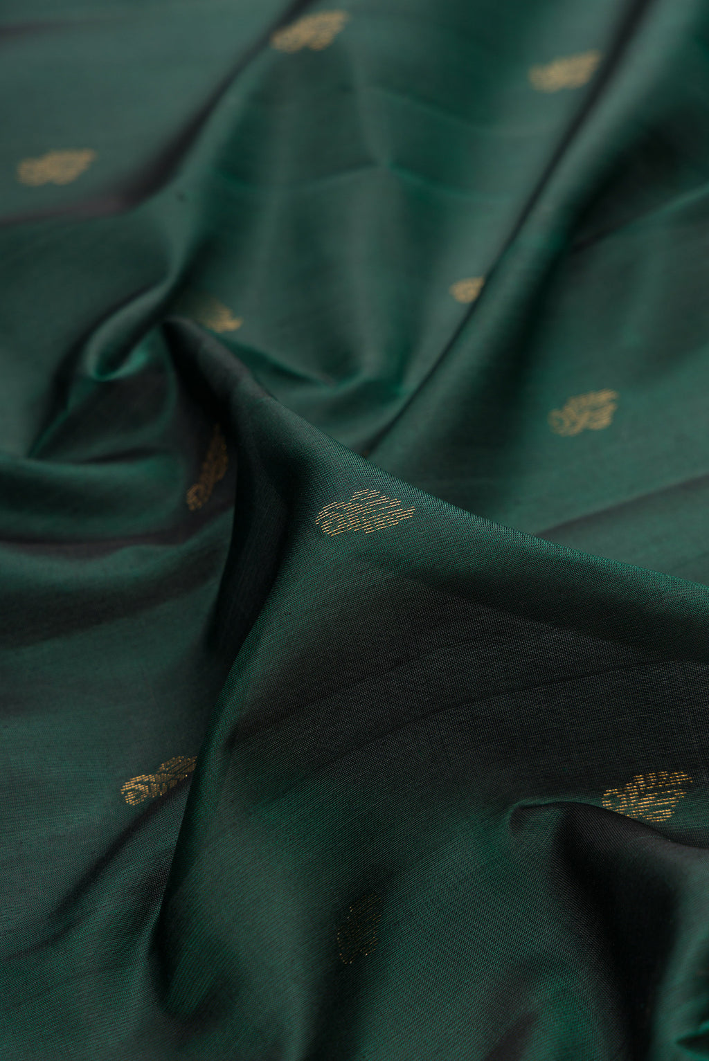 Close up of Pure Silk Bottle Green Soft Saree with Zari Butta on the body and Zari Border.  displaying folds