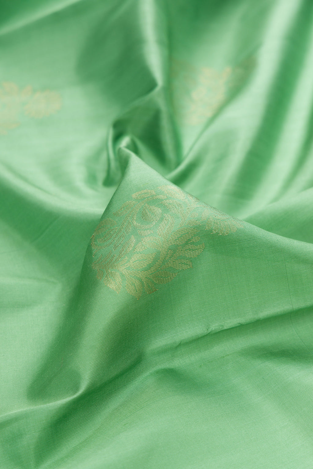 Close up of Pure Silk Light Green Soft Saree with Zari Butta on the body and Zari Border.  displaying folds