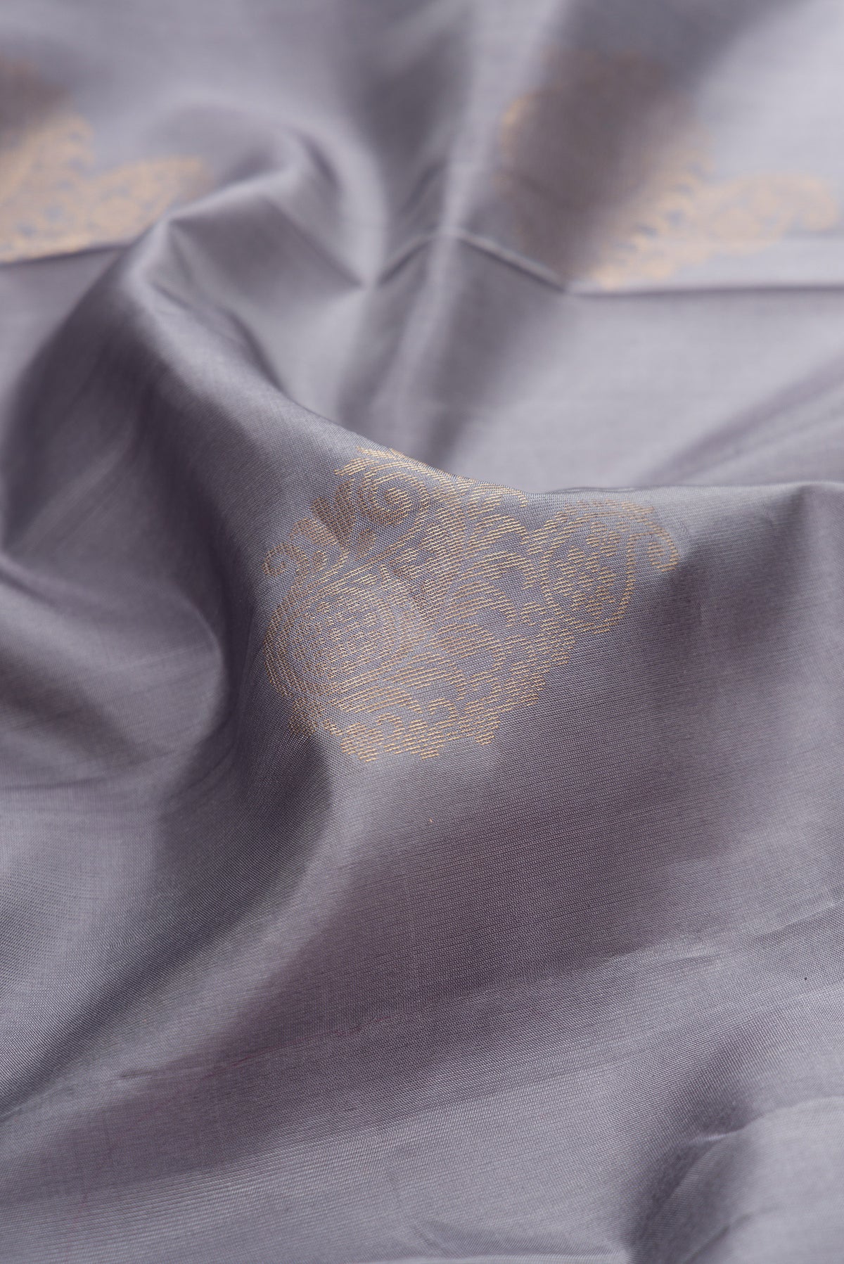 Close up of Pure Silk Grey Soft Saree with Zari Butta on the body and Zari Border.  displaying folds