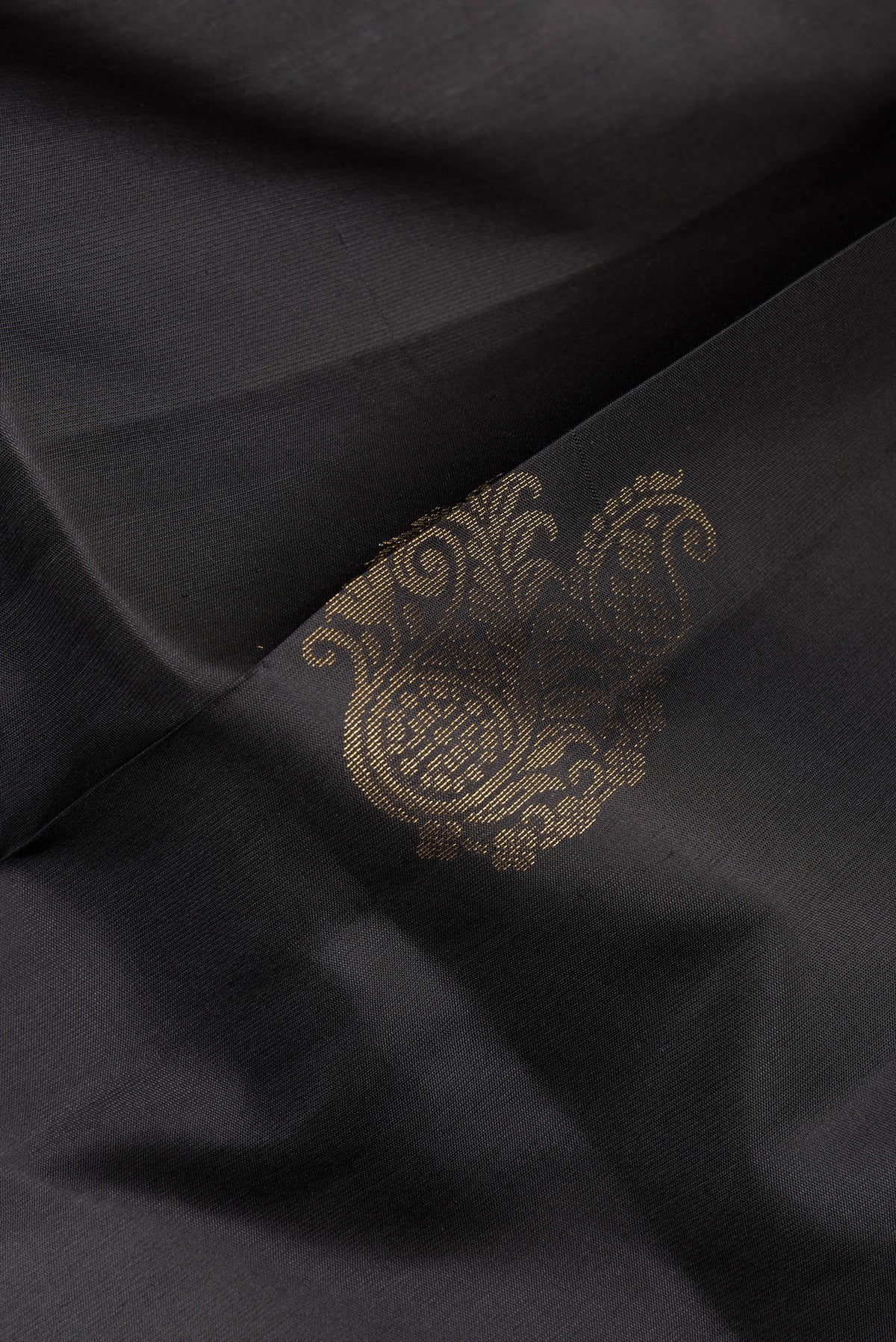 Close up of Pure Silk Black Soft Saree with Zari Butta on the body and Zari Border.  displaying folds
