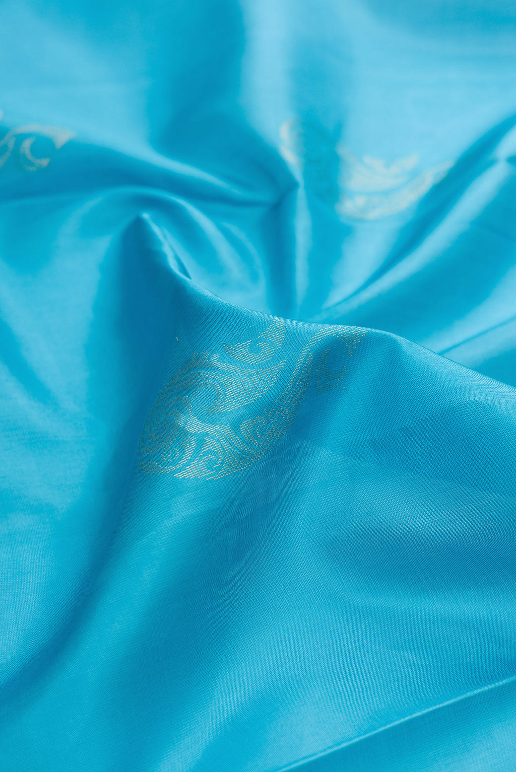 Close up of Pure Silk Sky Blue Soft Saree with Zari Butta on the body and Zari Border.  displaying folds