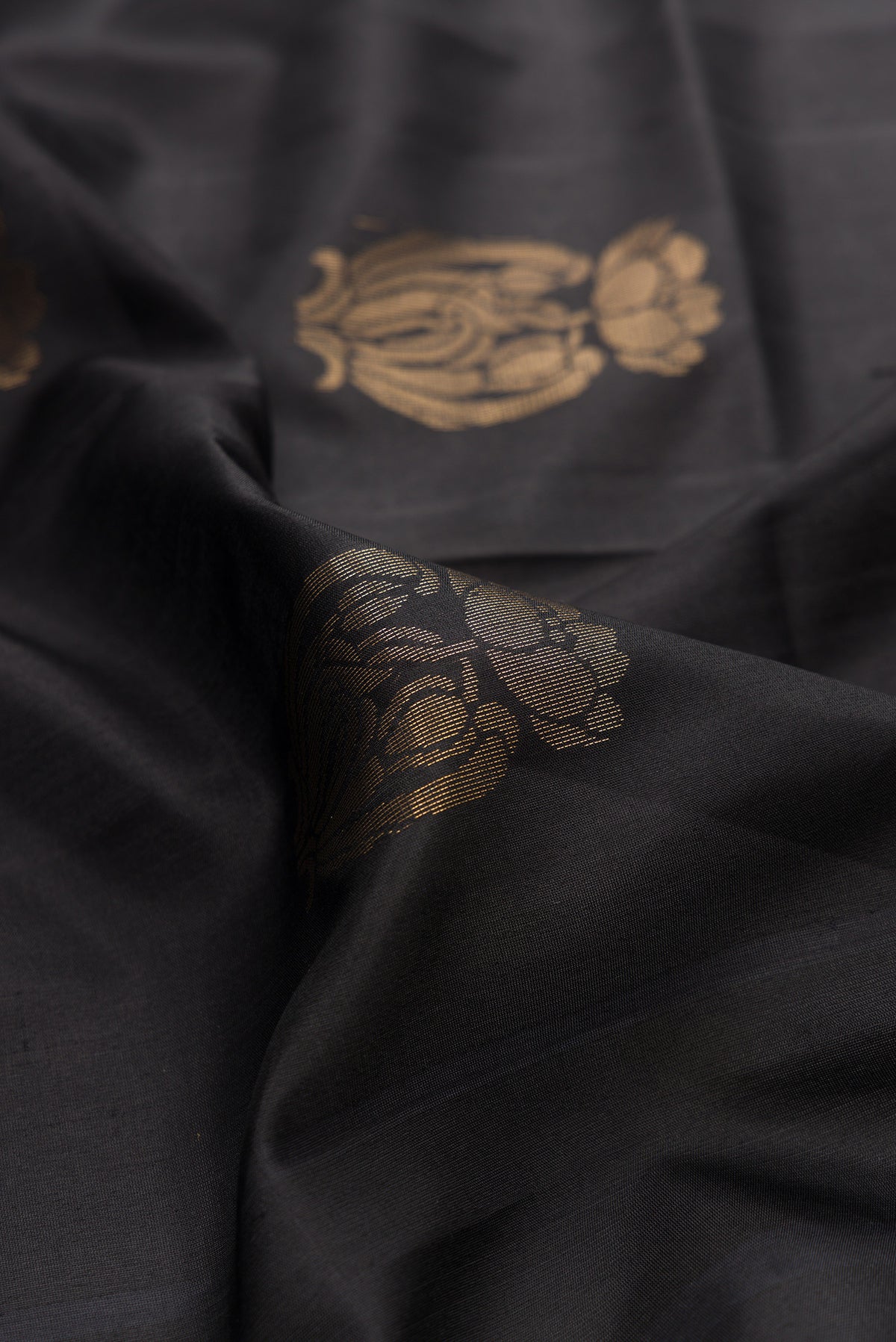 Close up of Pure Silk Black Soft Saree with Zari Butta on the body and Zari Border.  displaying folds