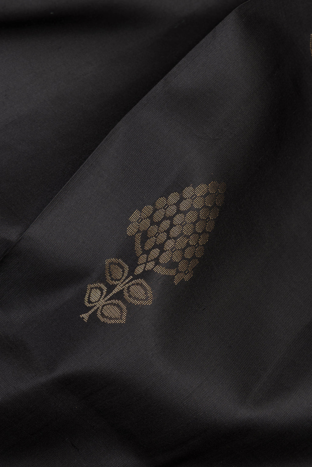 Close up of Pure Silk Black Soft Saree with Zari Butta on the body and Zari Border.  displaying folds
