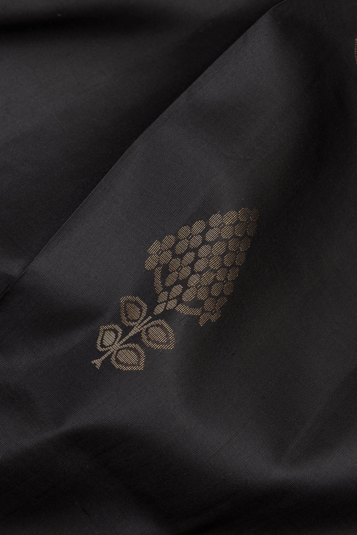 Close up of Pure Silk Black Soft Saree with Zari Butta on the body and Zari Border.  displaying folds