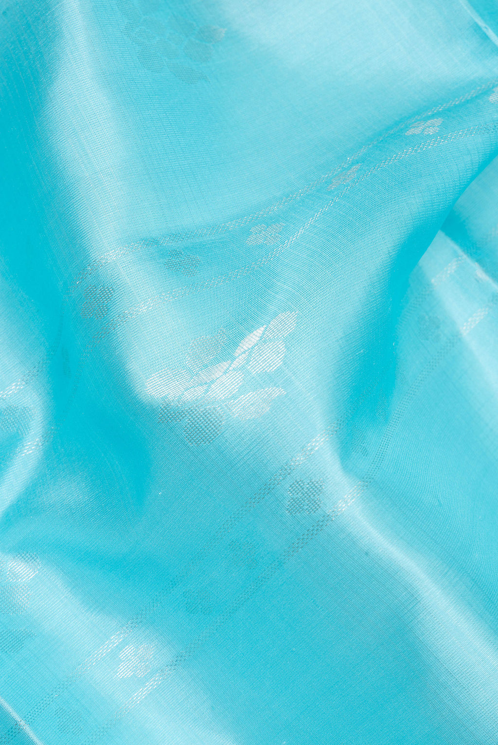 Close up of Pure Silk Sky Blue Soft Saree with Zari Butta on the body and Zari Border.  displaying folds