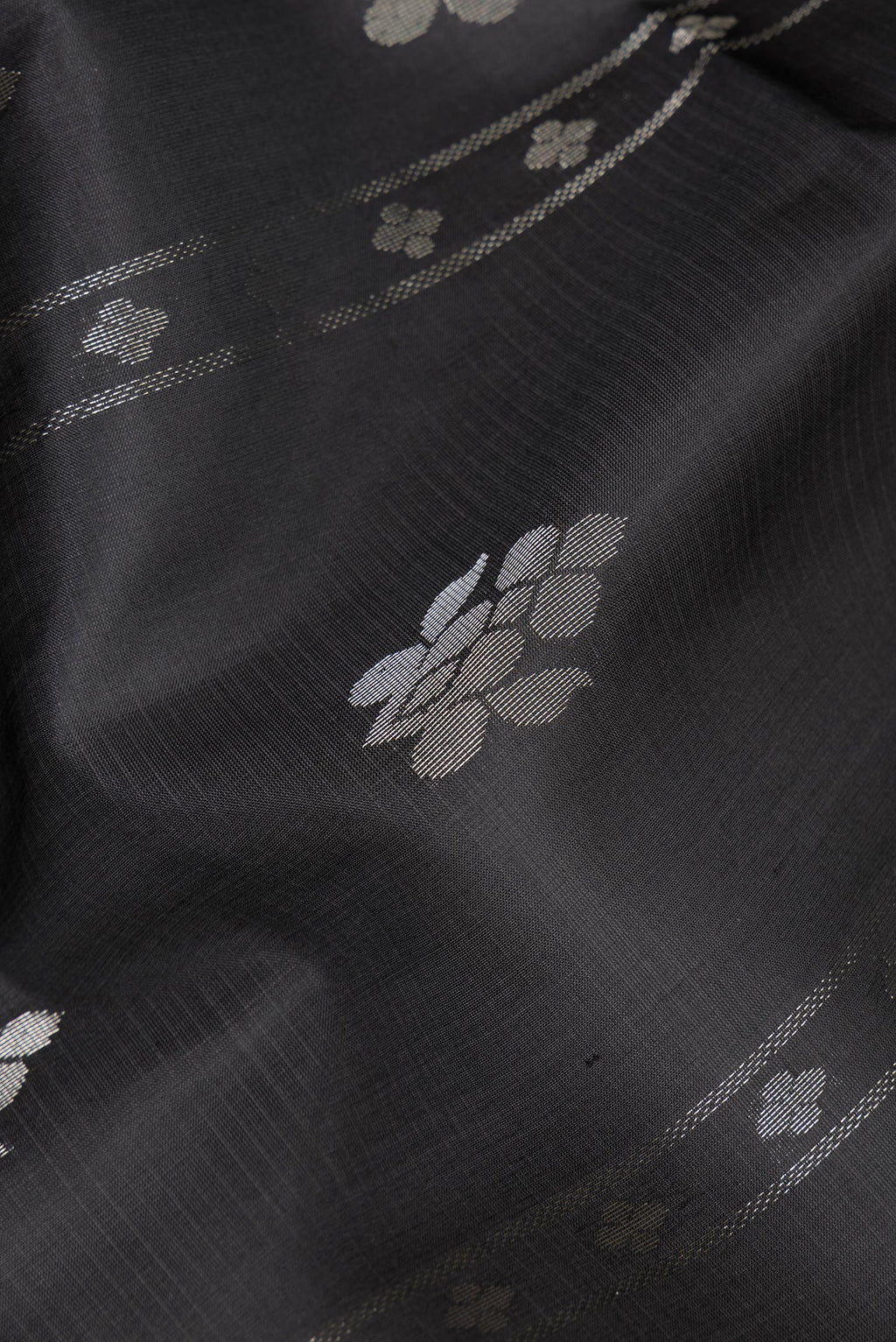 Close up of Pure Silk Black Soft Saree with Zari Butta on the body and Zari Border.  displaying folds