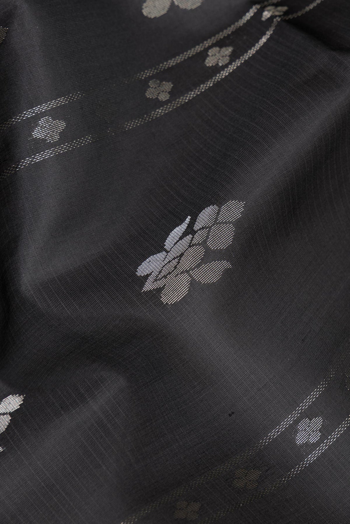 Close up of Pure Silk Black Soft Saree with Zari Butta on the body and Zari Border.  displaying folds