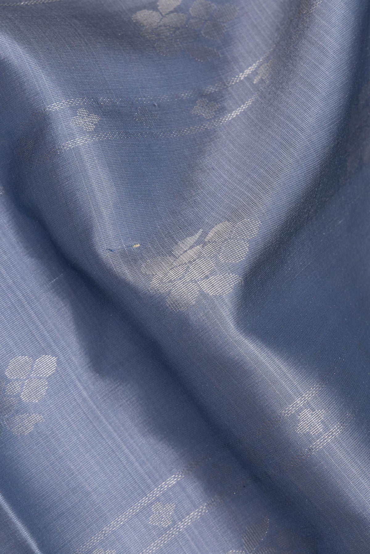 Close up of Pure Silk Grey Dual Tone Soft Saree with Zari Butta on the body and Zari Border.  displaying folds