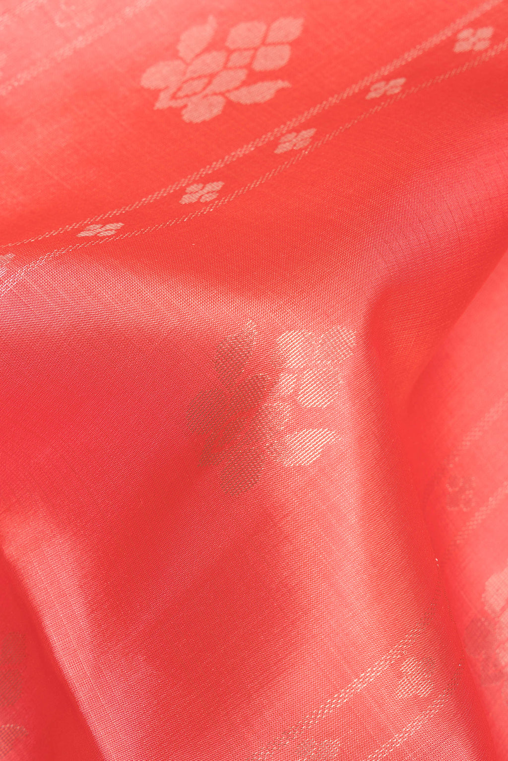 Close up of Pure Silk Coral Soft Saree with Zari Butta on the body and Zari Border.  displaying folds