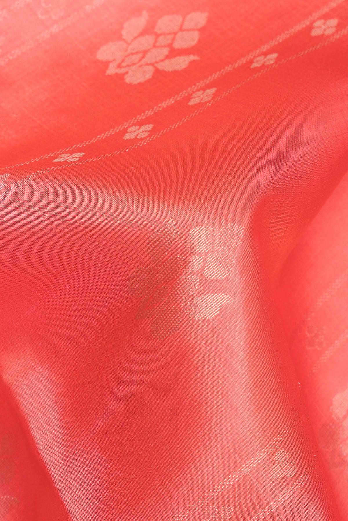 Close up of Pure Silk Coral Soft Saree with Zari Butta on the body and Zari Border.  displaying folds