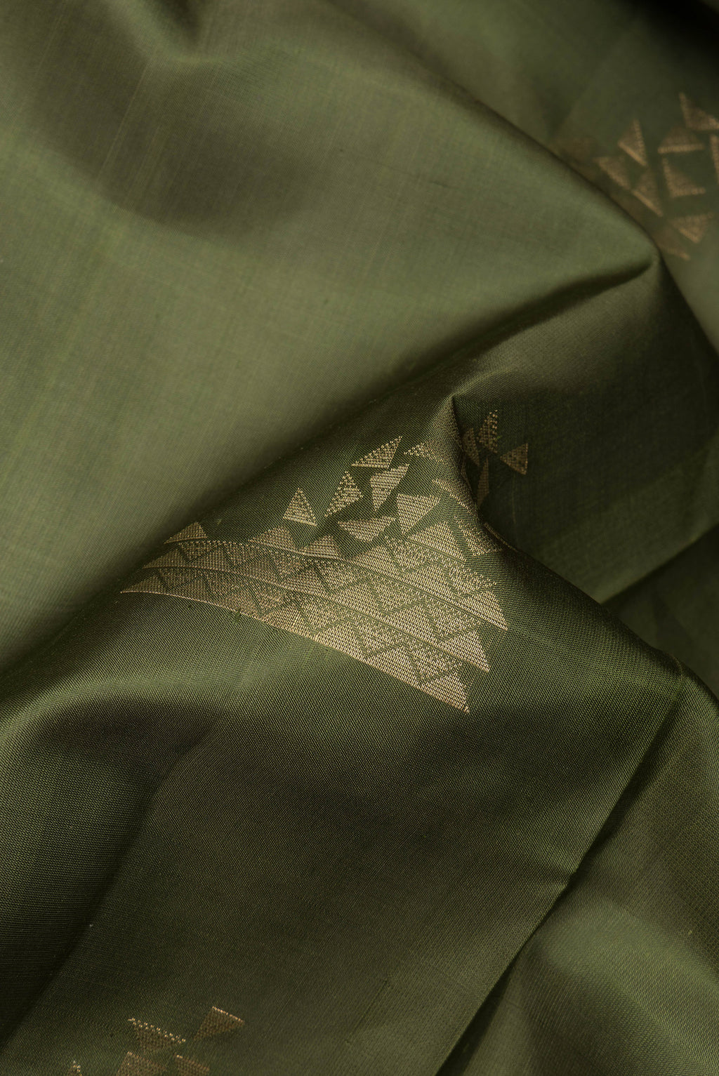 Close up of Pure Silk Olive Green Soft Saree with Zari Butta on the body and Zari Border.  displaying folds