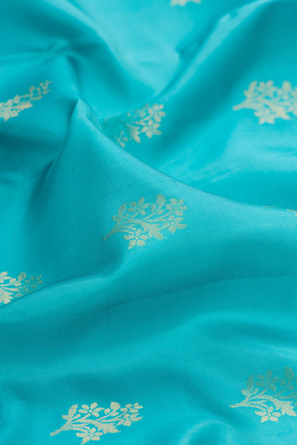 Close up of Pure Silk Turquoise Soft Saree with Zari Butta on the body and Zari Border.  displaying folds