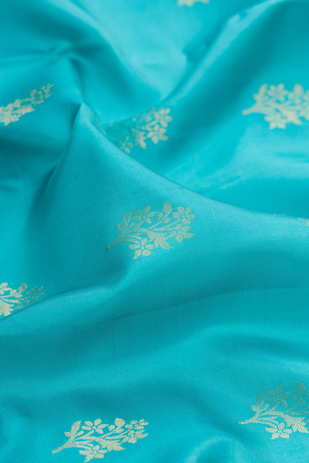 Close up of Pure Silk Turquoise Soft Saree with Zari Butta on the body and Zari Border.  displaying folds