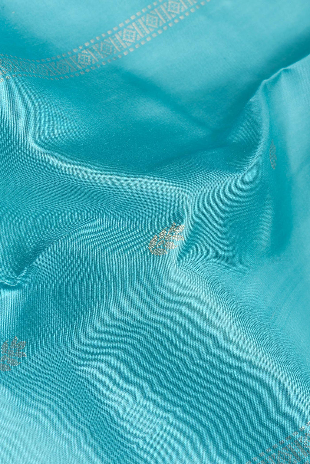 Close up of Pure Silk Sky Blue Soft Saree with Zari Butta on the body and Zari Border.  displaying folds