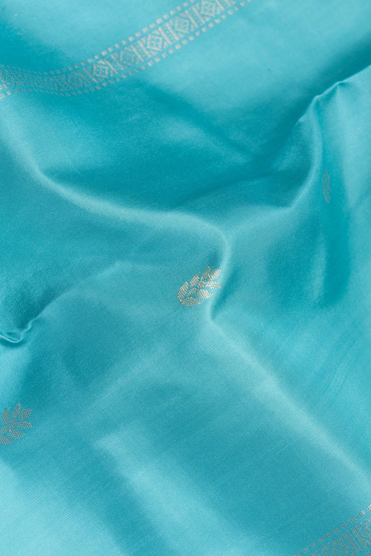 Close up of Pure Silk Sky Blue Soft Saree with Zari Butta on the body and Zari Border.  displaying folds