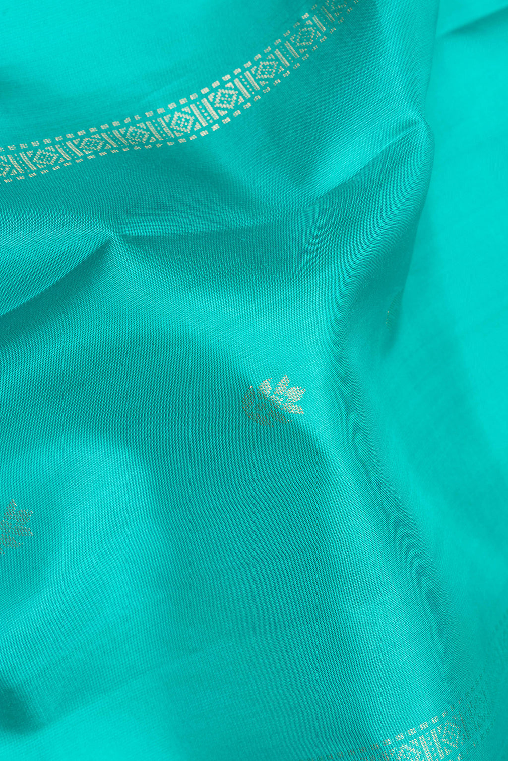 Close up of Pure Silk Turquoise Dual Tone Soft Saree with Zari Butta on the body and Zari Border.  displaying folds